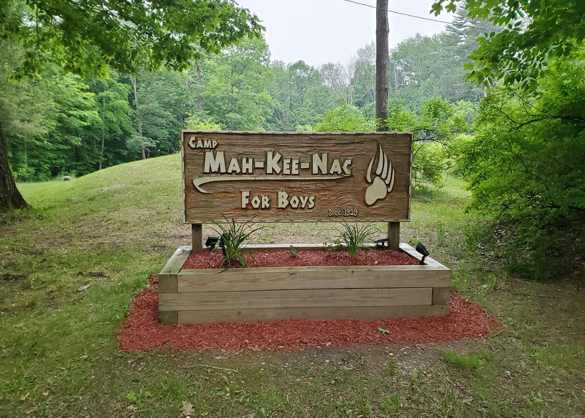 Wood sign saying " Camp Mah-Kee-Nac For Boys".