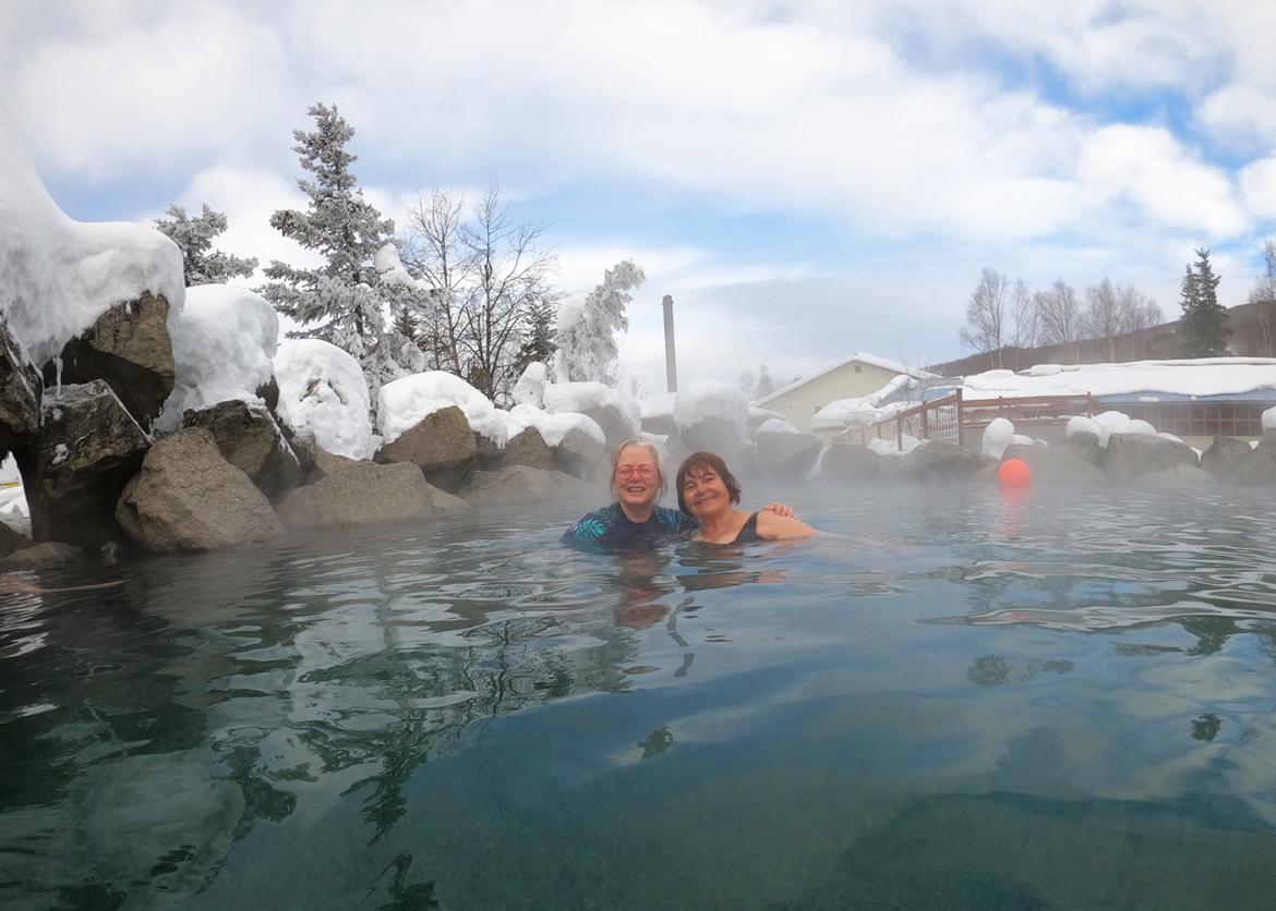 Two smiling people in a steaming hot spring.