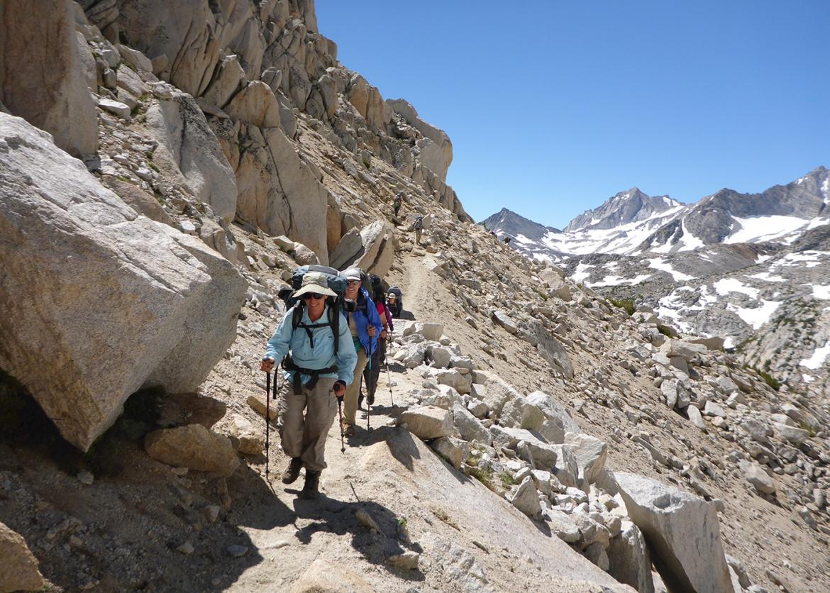Trip participants hiking on rocky mountain trail