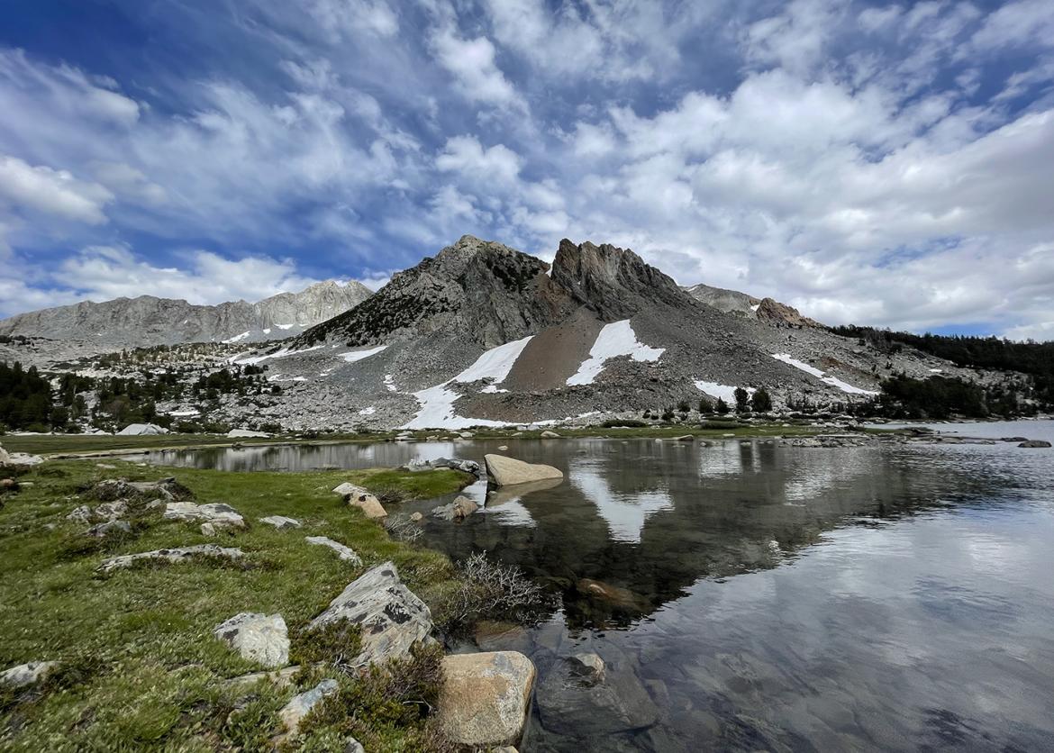 Lake in front of a Sierra mountain peak with patches of snow