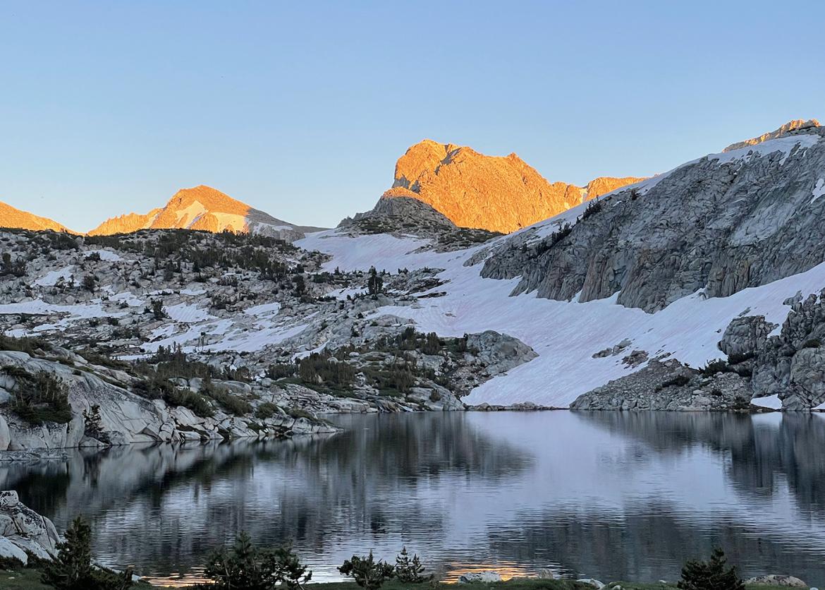 Snowy Sierra mountain peak with a reflective lake in the foreground