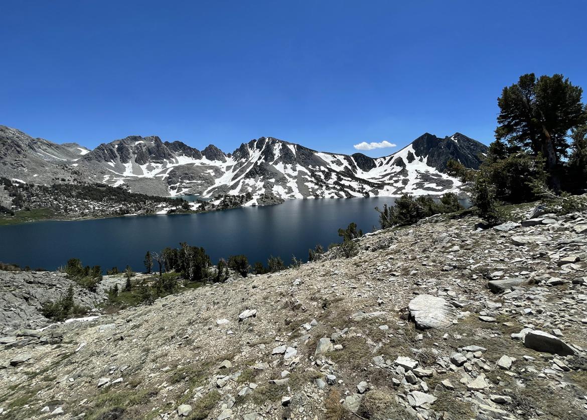 Lake in front of a Sierra mountain peak with patches of snow