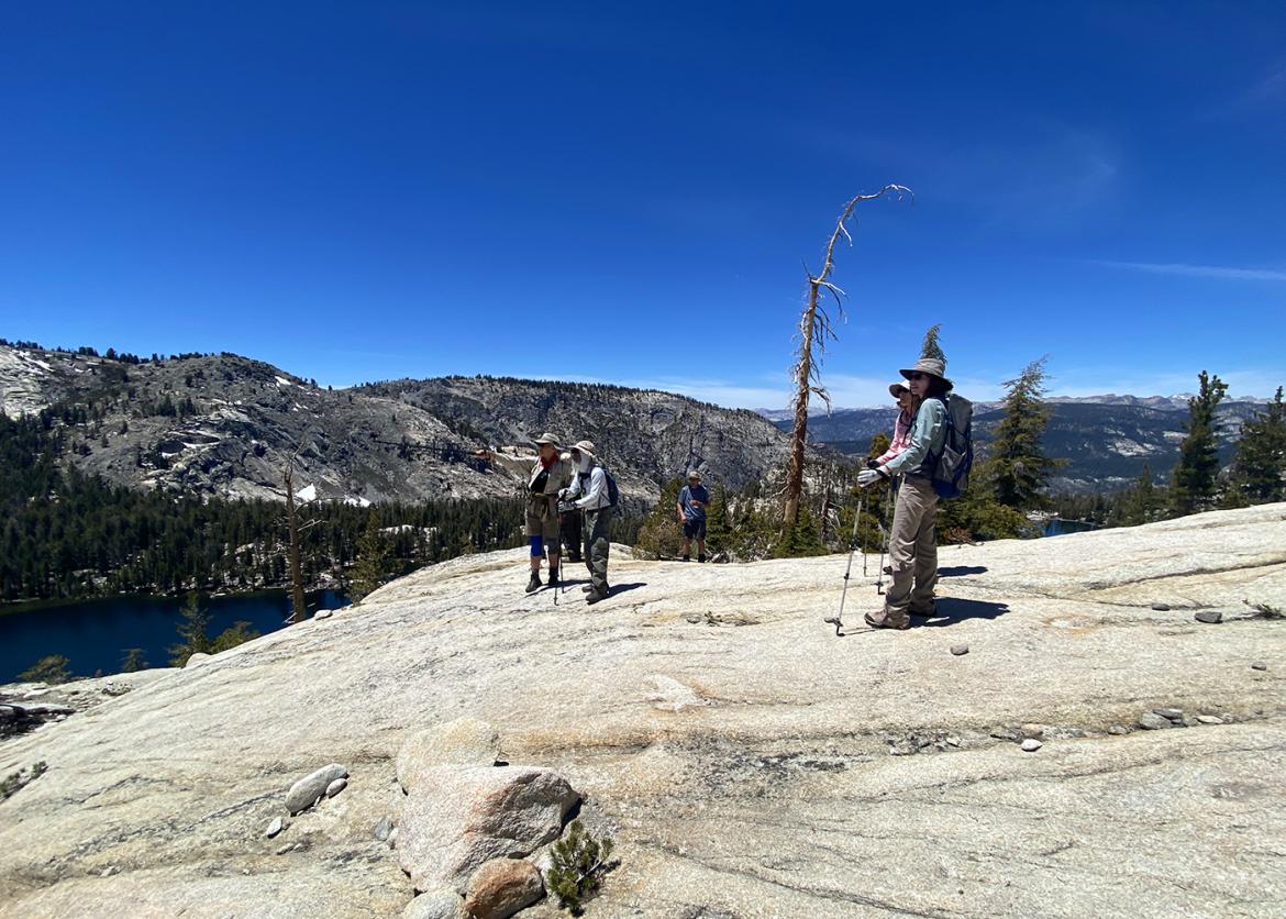 Trip participants take in the view atop a smooth rock face in Yosemite