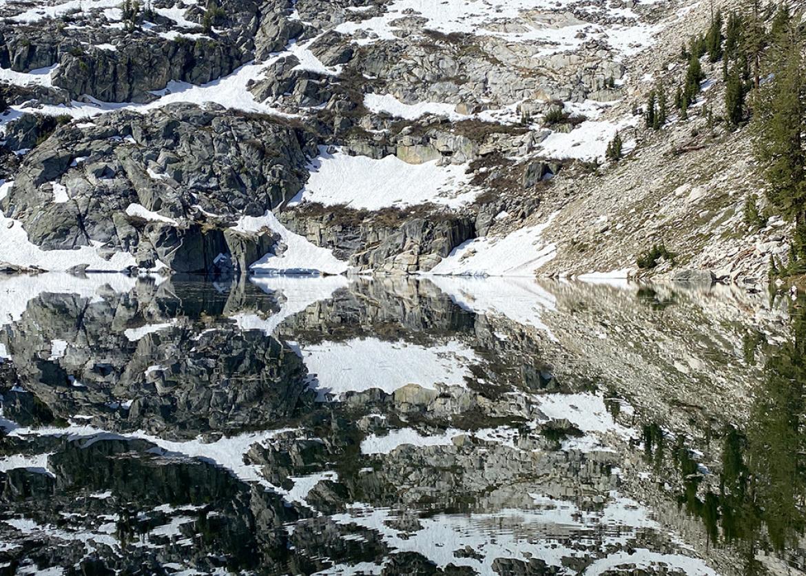A calm lake mirroring a snowy mountainside 