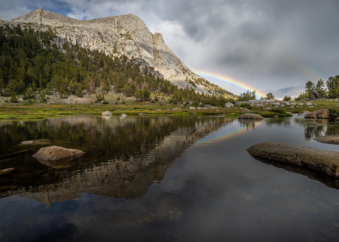 Photo of mountain landscape and lake with cloudy skies and rainbow