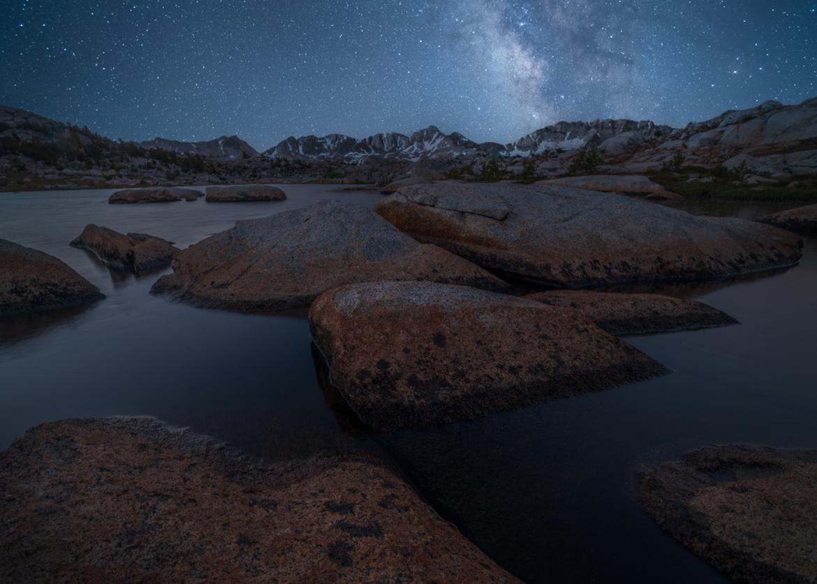 Photo of milky way and starry sky over mountain, lake, and rocks