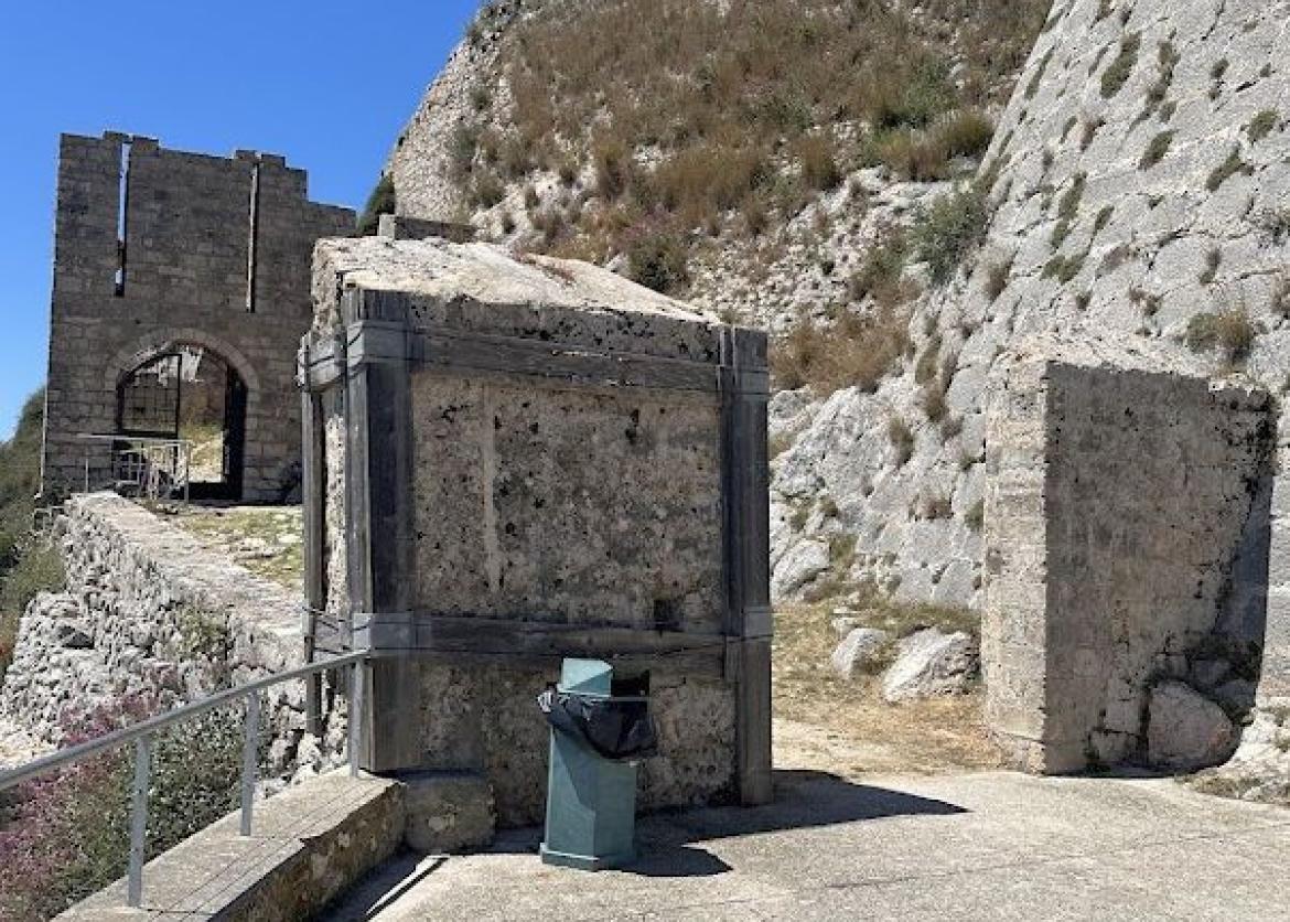 An oddly placed trash can among greek ruins.