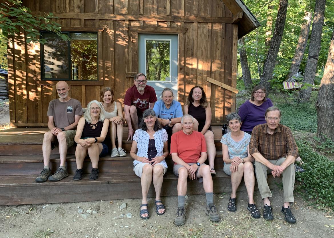 People smiling and sitting in front of a cabin.