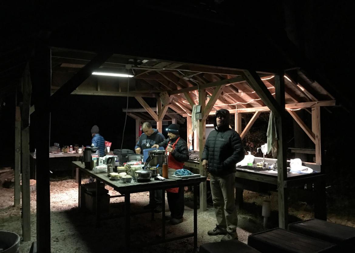 A group of people dressed in layers, cooking in the dark