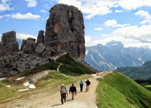 Four hikers on a trail. The trail leads up to a towering outcropping of rock.