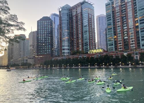 Kayakers on Chicago River, surrounded by towering skyscrapers
