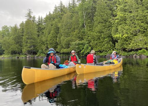 Two yellow canoes with trip participants on a river