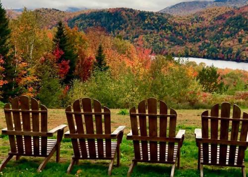 Four adirondack chairs facing view of forested hillside in autumn