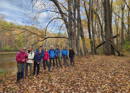 Trip participants pose for photo along a hiking trail, with autumn forest in background