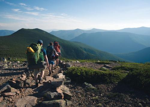Teens hike a rocky mountain trail.